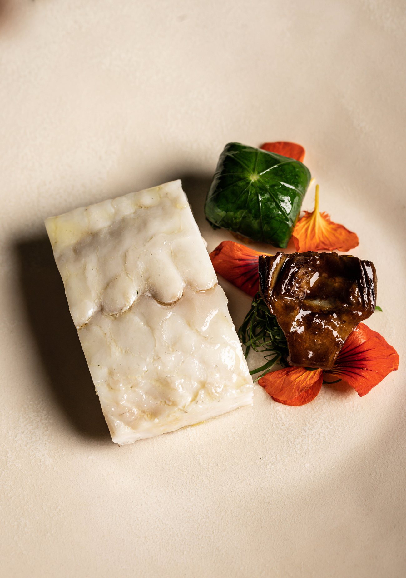 Une assiette de Substance : feuille verte, fleurs et voile crémeux
